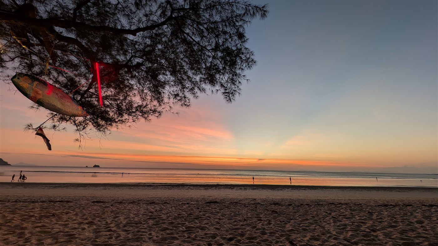 Sonnenuntergang am Strand der Samosa Bar mit dekorativem Fisch im Baum